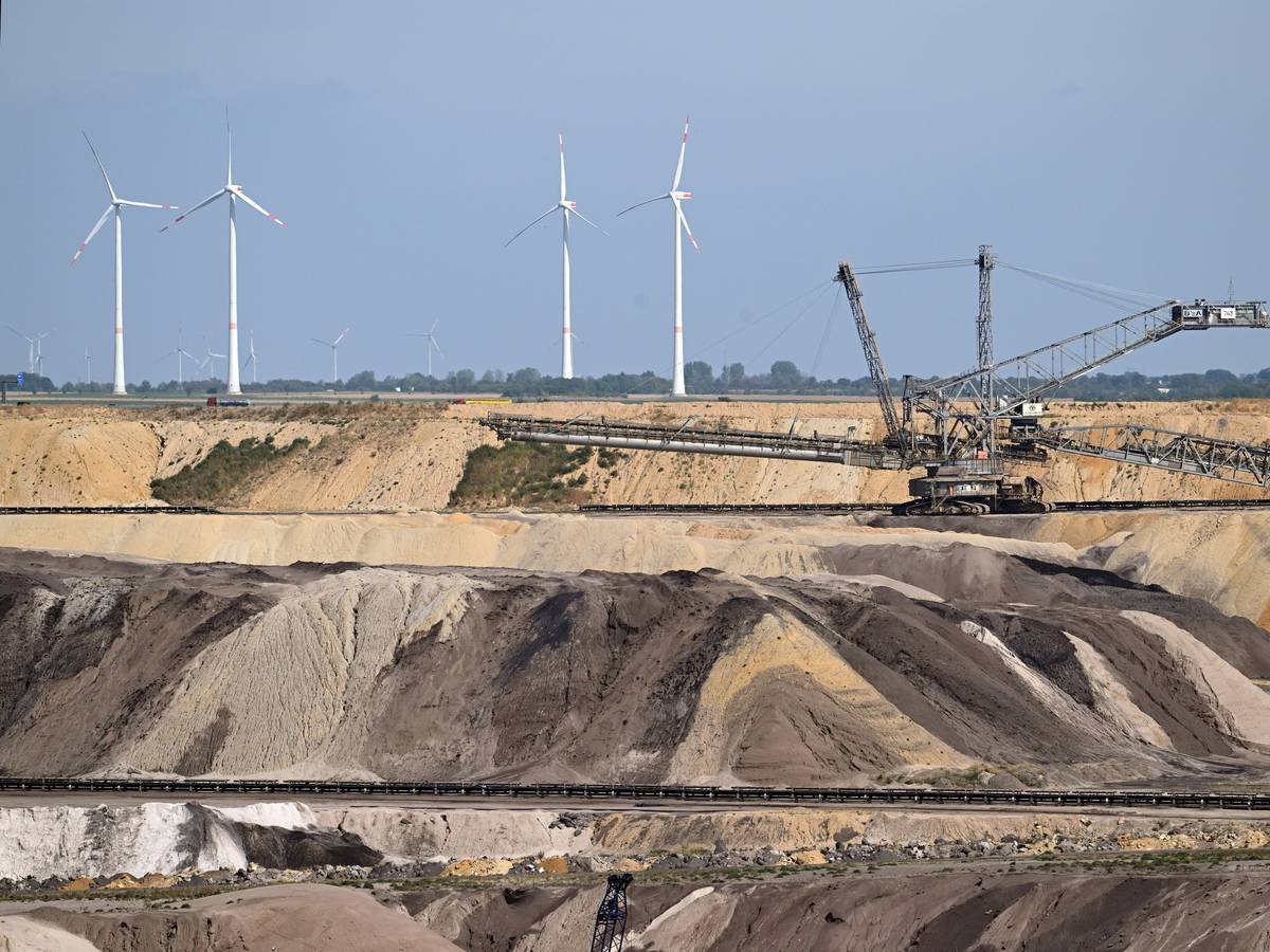 Ein Schaufelradbagger arbeitet im Braunkohletagebau Garzweiler. Im Hintergrund sind Windräder zu sehen. Das Foto stammt aus dem September 2022.