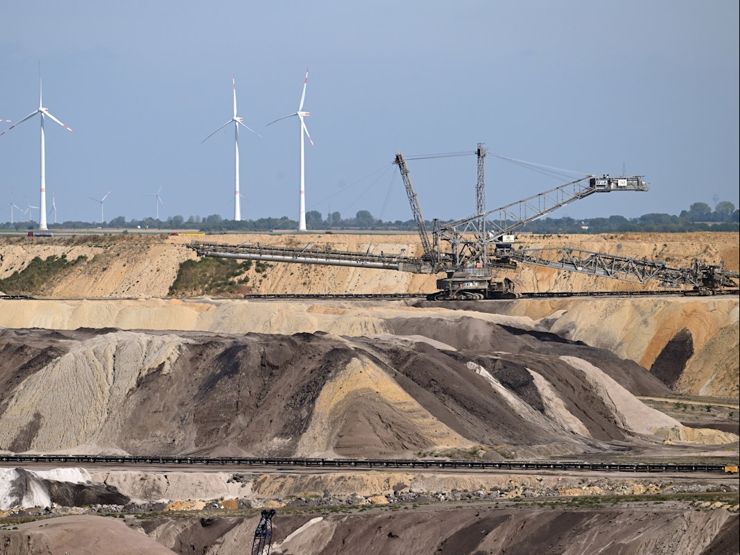 Ein Schaufelradbagger arbeitet im Braunkohletagebau Garzweiler. Im Hintergrund sind Windräder zu sehen. Das Foto stammt aus dem September 2022.