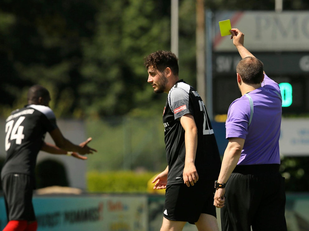 Ein Schiedsrichter zeigt die Gelbe Karte.