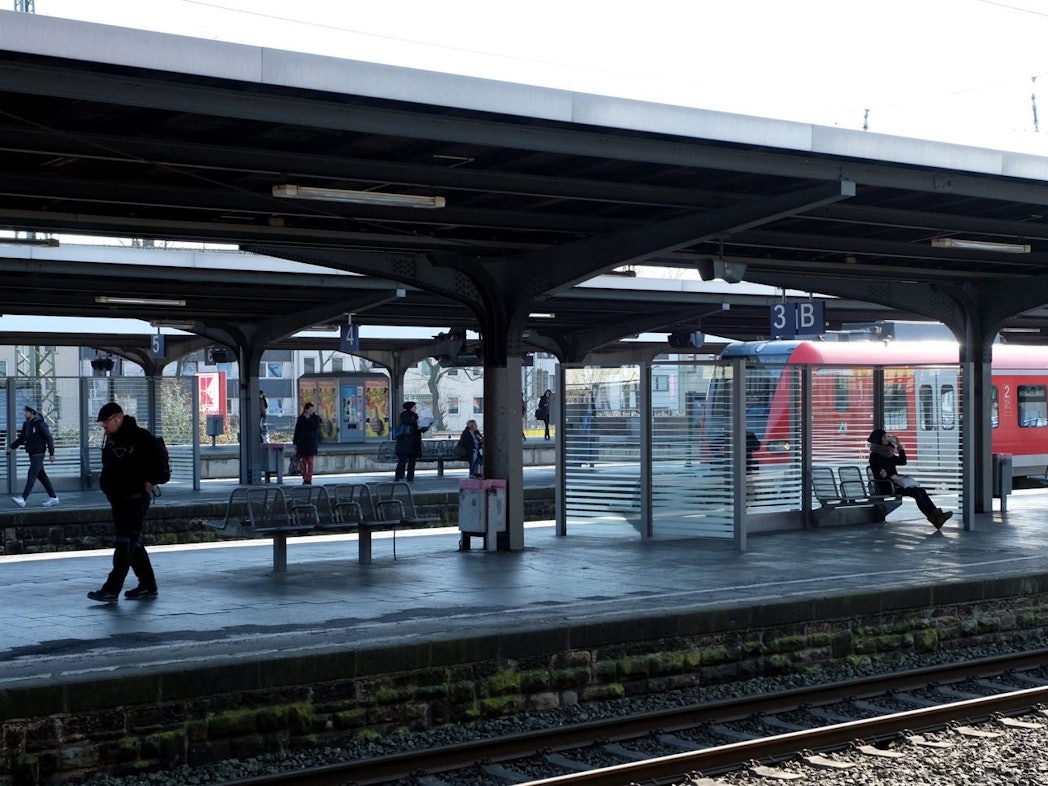 Menschen gehen über einen Bahnsteig am Bahnhof in Köln-Mülheim.