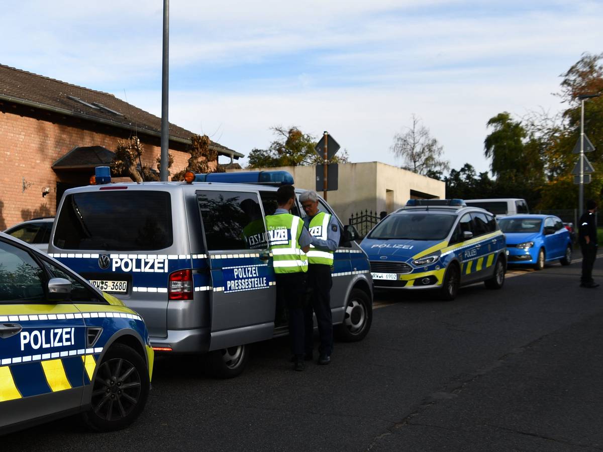 Polizeikräfte und Polizeifahrzeuge stehen in einer Straße.