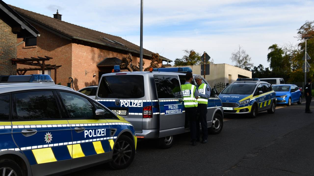 Polizeikräfte und Polizeifahrzeuge stehen in einer Straße.