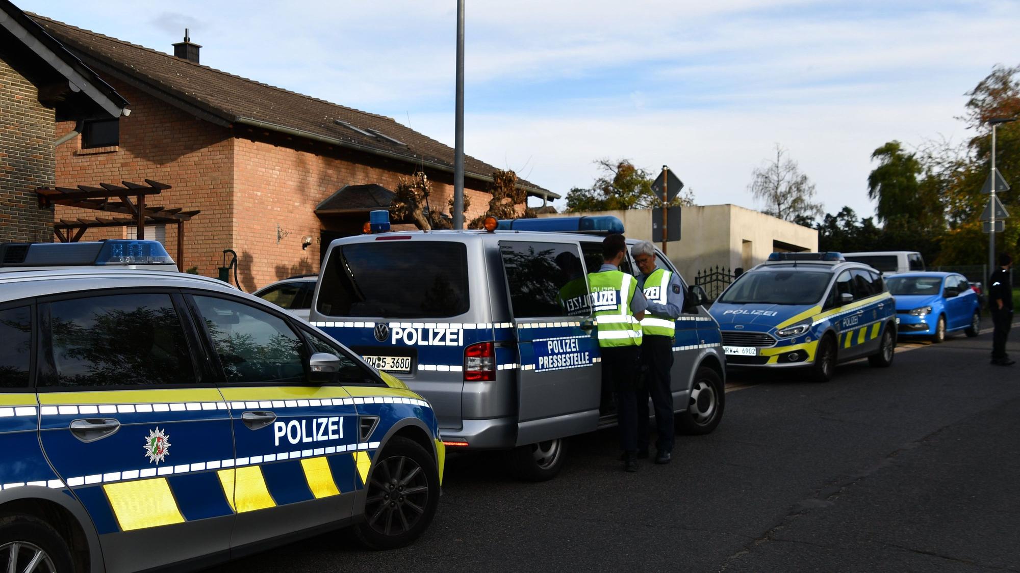 Polizeikräfte und Polizeifahrzeuge stehen in einer Straße.