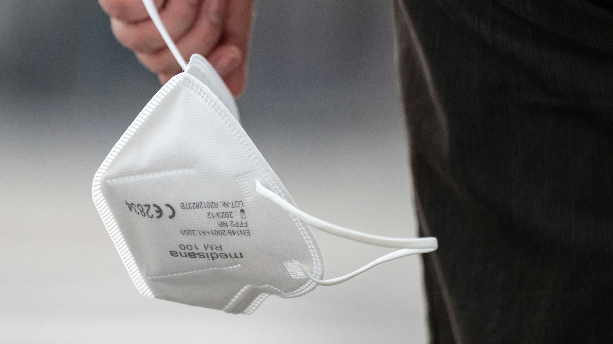 Eine Passantin trägt eine FFP2-Maske in der Hand.