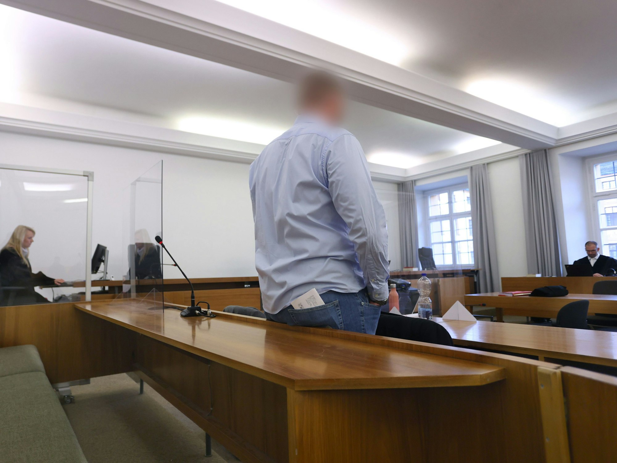 Mann steht in der Anklagebank in einem Verhandlungsraum. Er soll eine Kollegin bei einem Bundeswehr-Einsatz vergewaltigt haben.