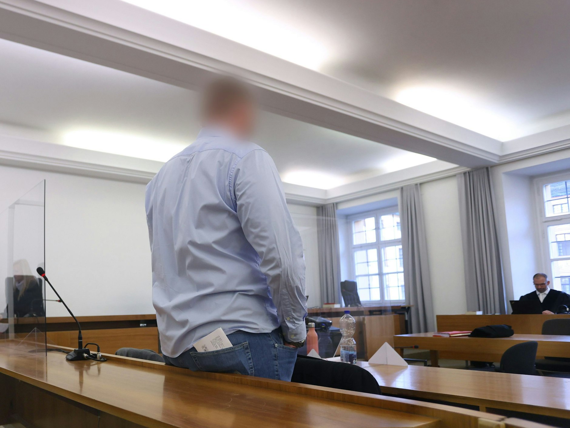 Mann steht in der Anklagebank in einem Verhandlungsraum. Er soll eine Kollegin bei einem Bundeswehr-Einsatz vergewaltigt haben.