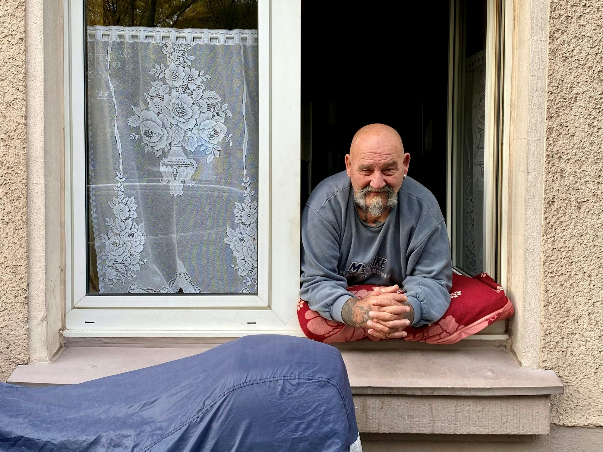 Herbert Niemeyer lehnt sich aus seinem Fenster und schaut in die Kamera.