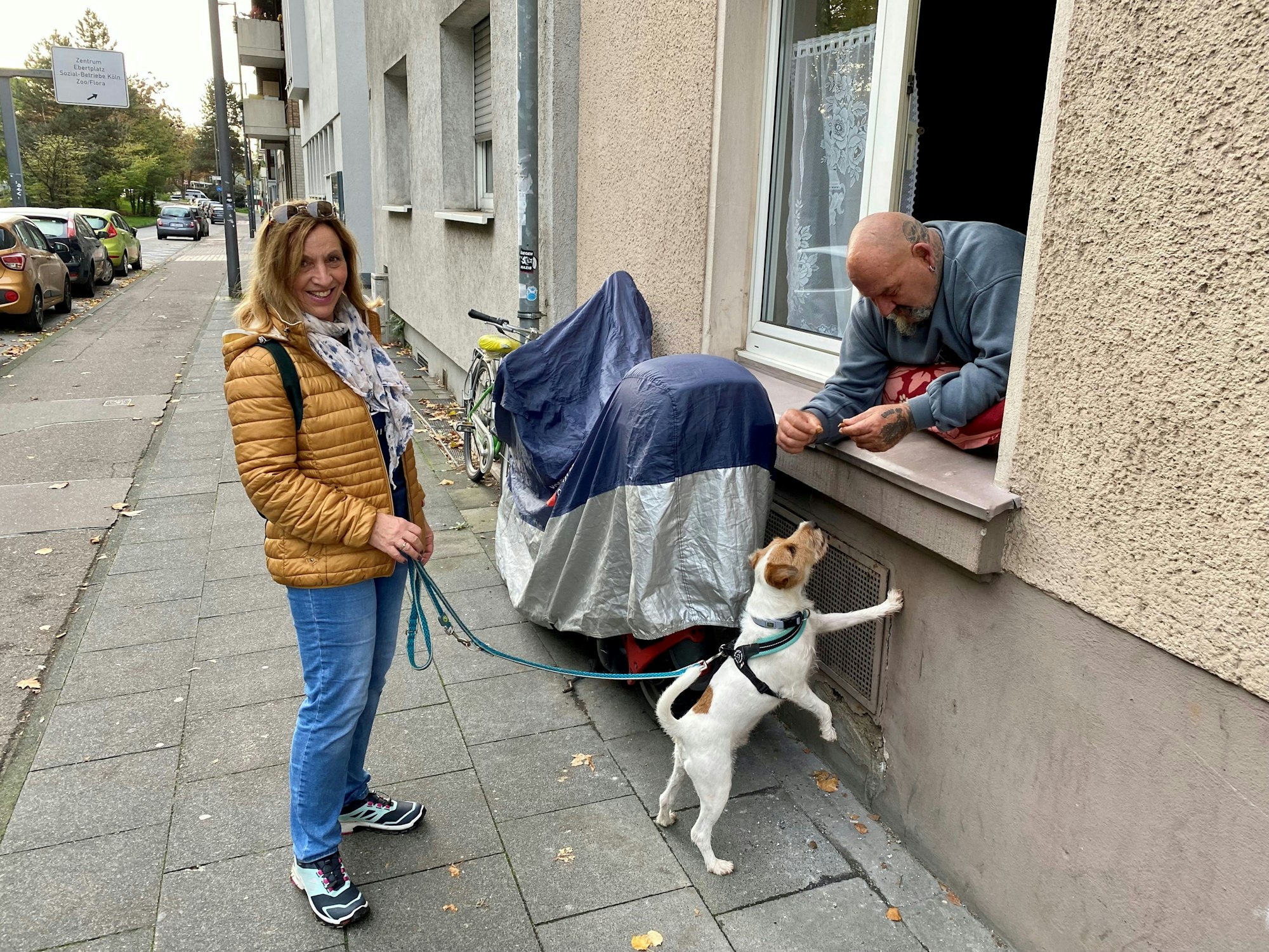 Eine Nachbarin und ihr Hund sprechen mit Herbert, der auf seinem Fensterbrett lehnt.