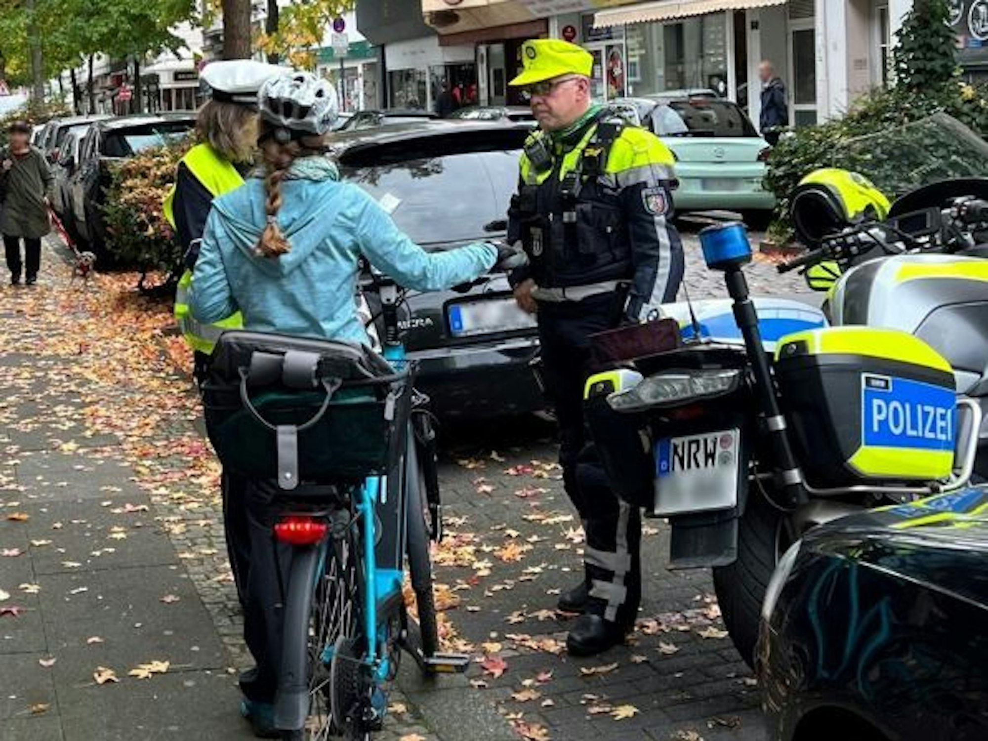 Die Polizei in Wuppertal im Gespräch mit einer Radfahrerin. Nach einem tödlichen Unfall wird der flüchtige Verursacher gesucht.