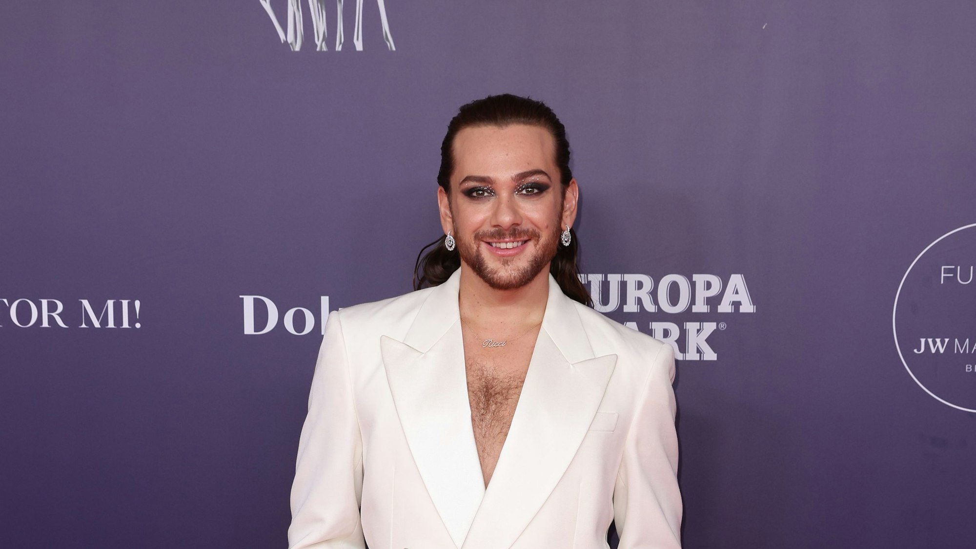 Entertainer Riccardo Simonetti in einem weißen Anzug auf dem roten Teppich.