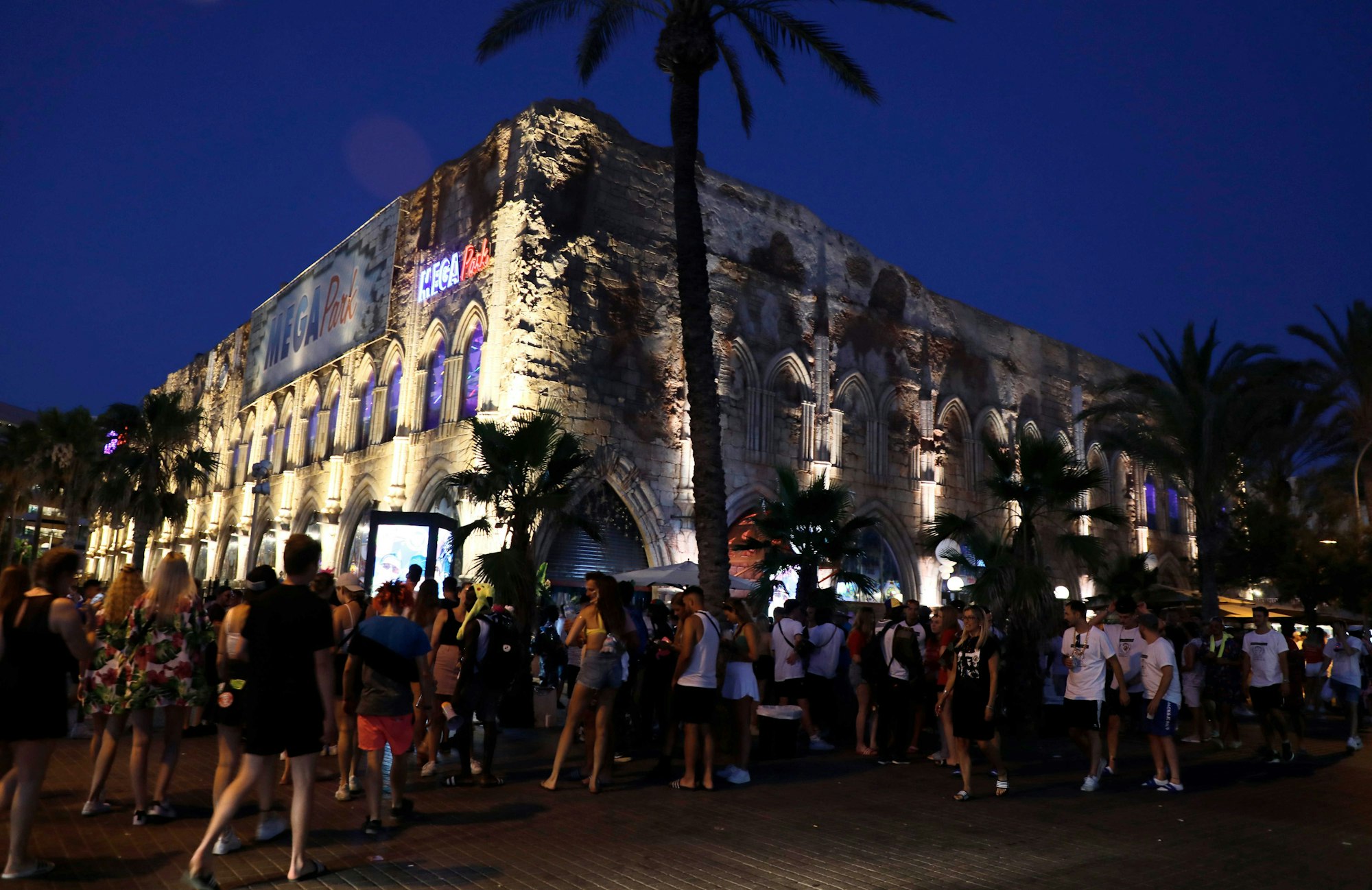 Menschen gehen neben dem Megapark am Strand von Arenal auf Mallorca vorbei.