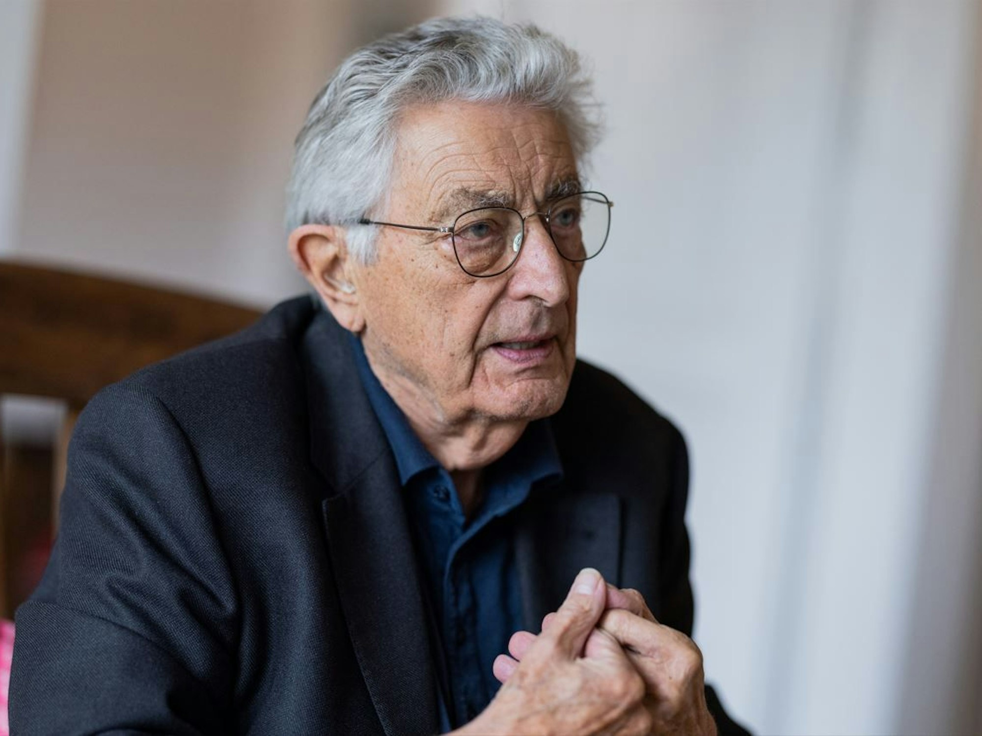 Gerhart Baum sitzt auf einem Stuhl und spricht. Der Ex-Innenminister wird 90 Jahre alt.