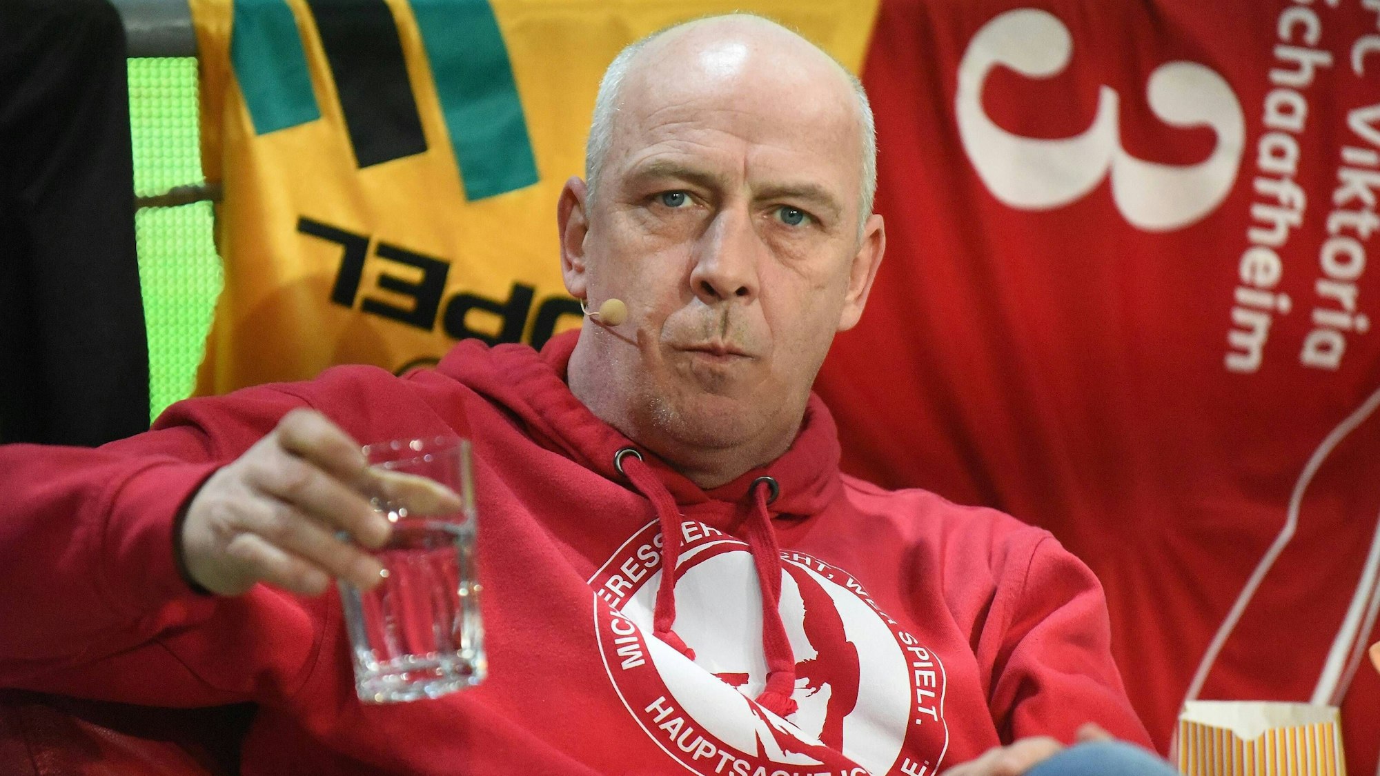 Mario Basler hält ein Wasserglas in der Hand.