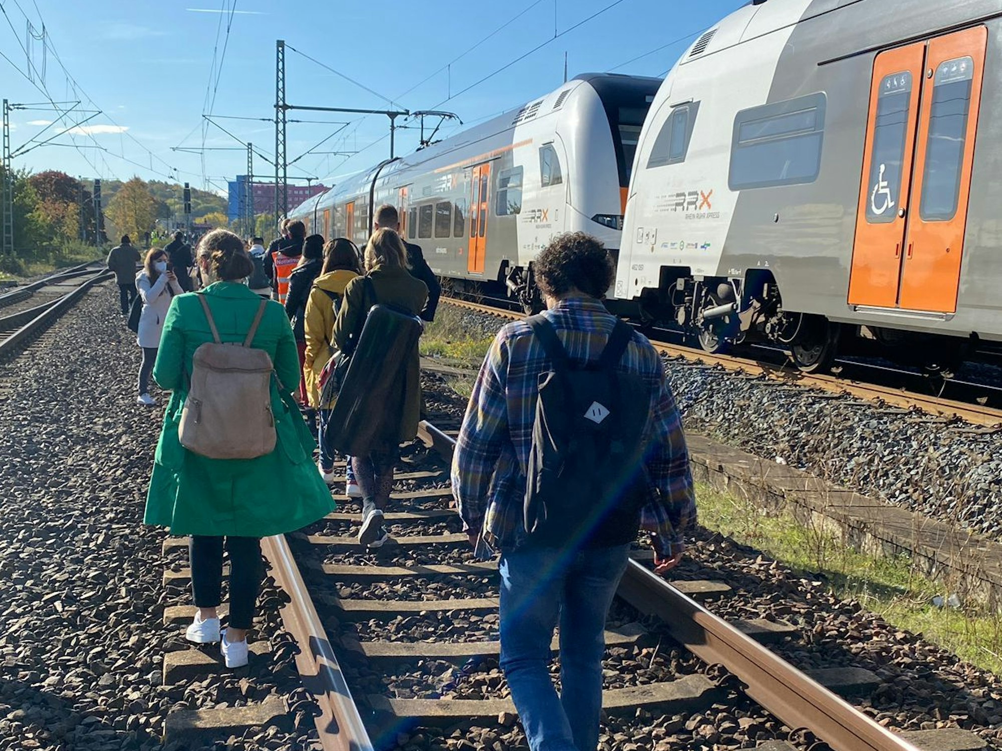Fahrgäste des RE6 in Köln gehen zu Fuß über die Gleise in Richtung Köln-Nippes.