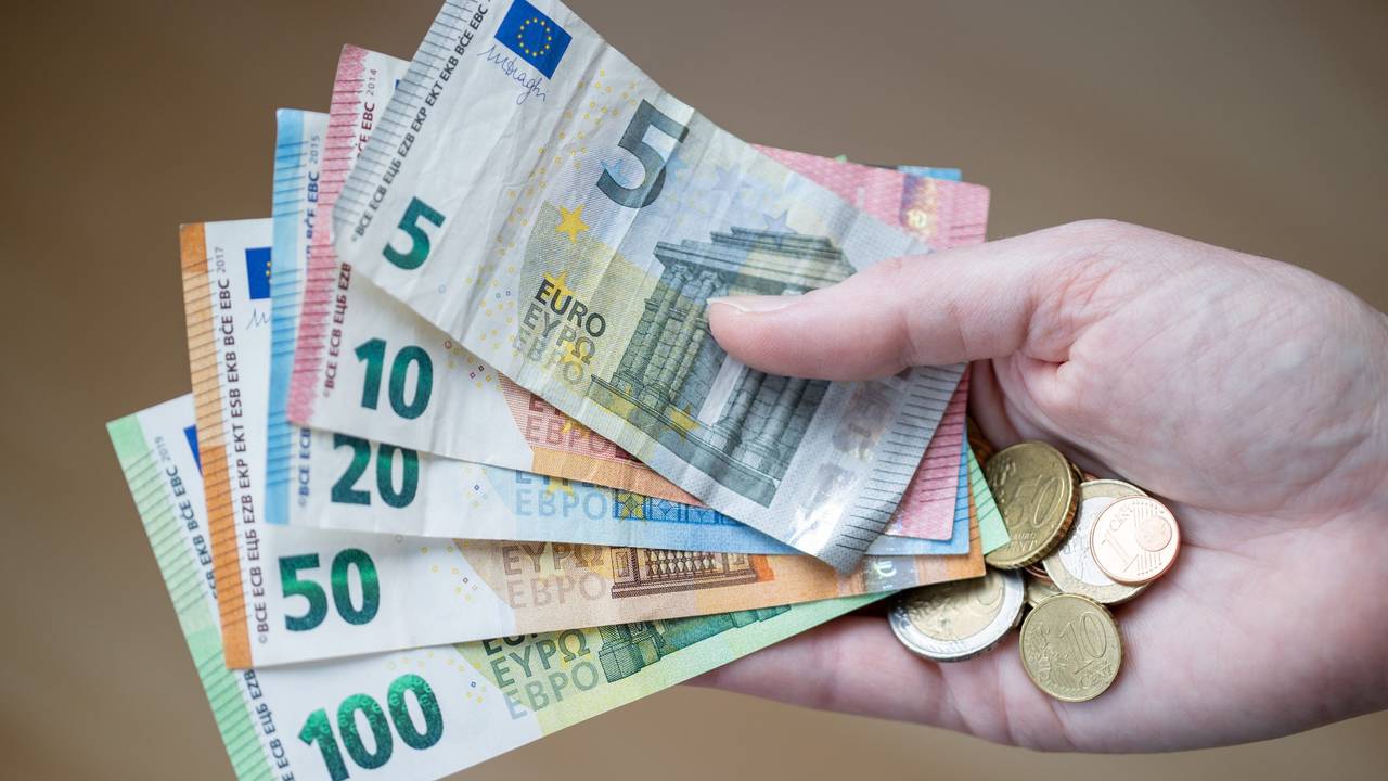 Eine Frau hält Geldscheine und Münzen in der Hand.
