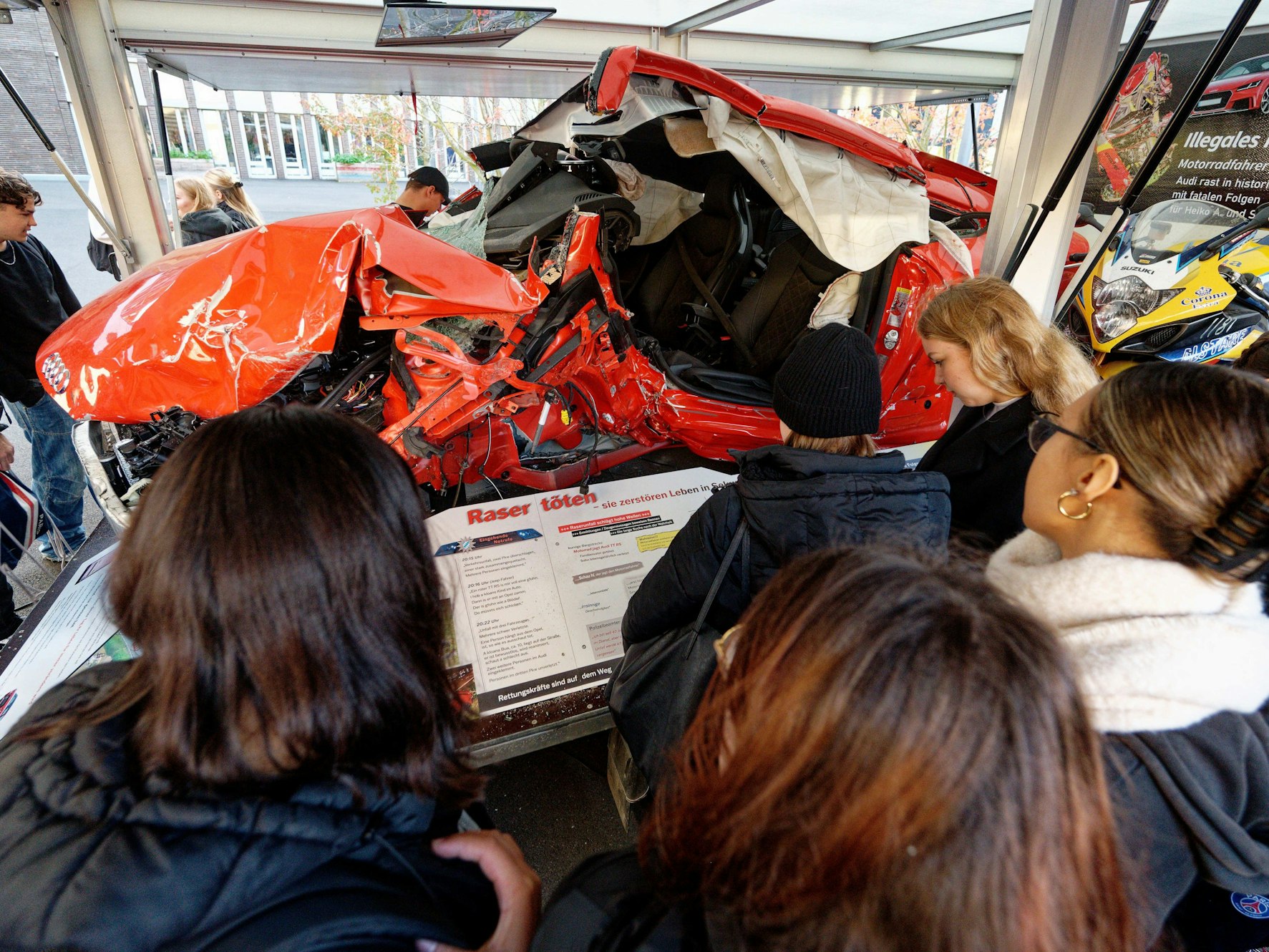 Schülerinnen und Schüler stehen in Köln vor dem Wrack eines Unfall-Autos. Die Aktion ist Teil eines Projekts der NRW-Regierung.