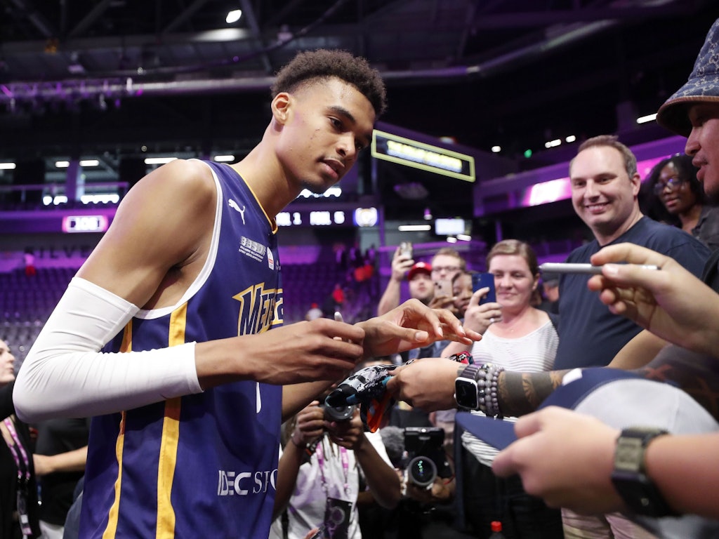 Basketballspieler Victor Wembanyama gibt in einer Halle Autogramme für Fans.