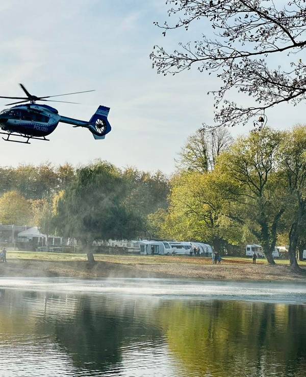 Ein Hubschrauber fliegt über einen See.