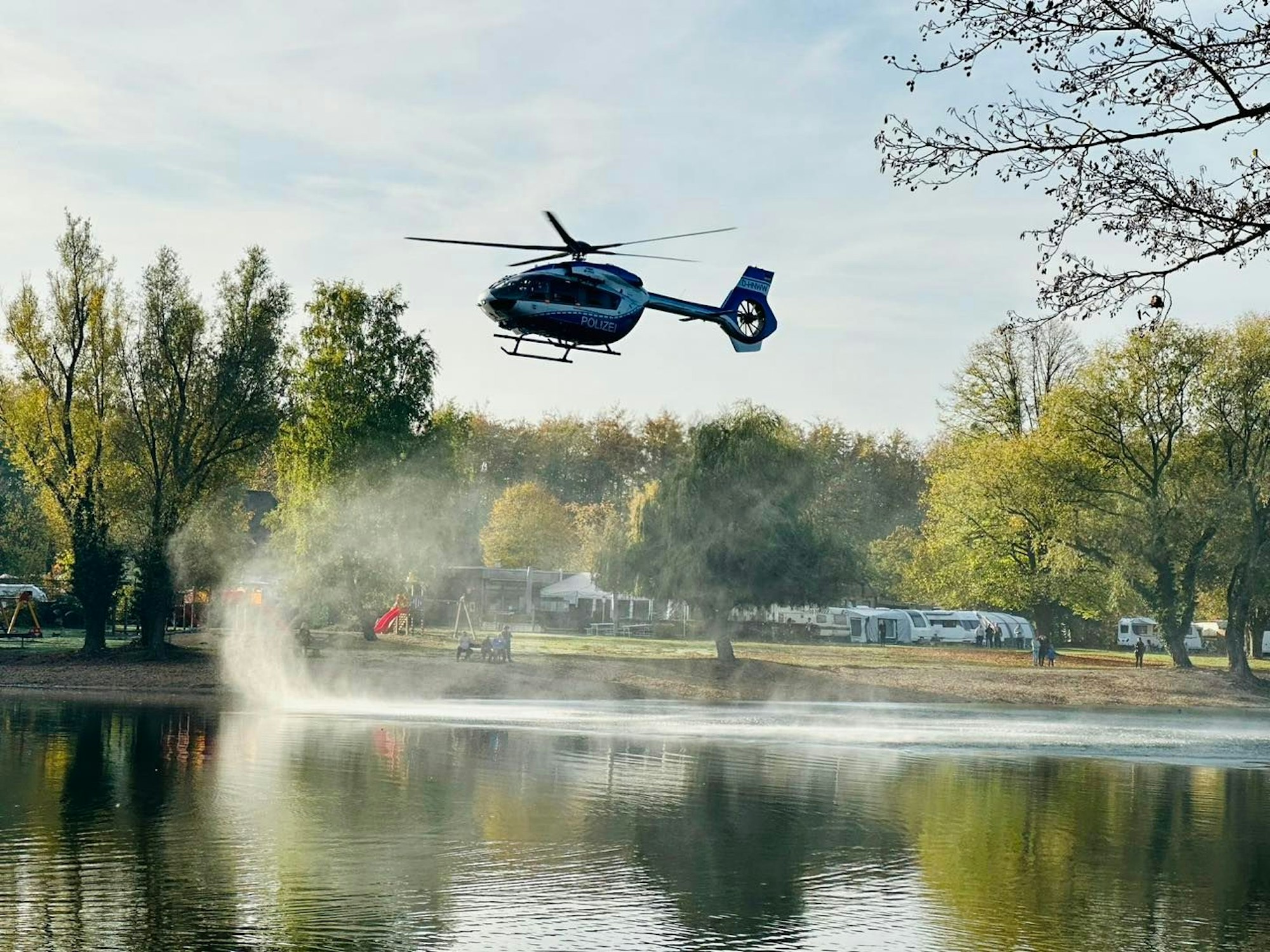 Ein Hubschrauber fliegt über einen See.