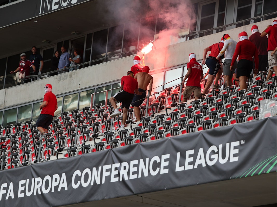 Fans laufen mit Pyrotechnik über eine Tribüne.