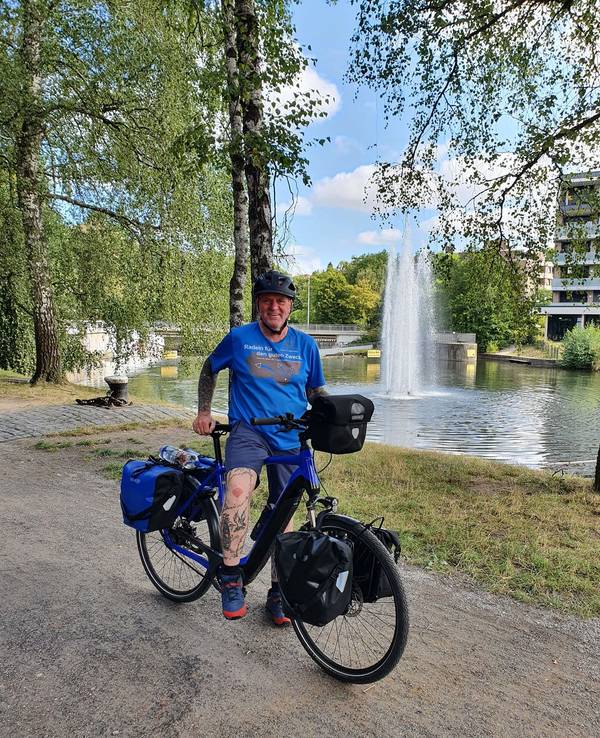 Oliver Trelenberg steht mit seinem Fahrrad vor einem See.