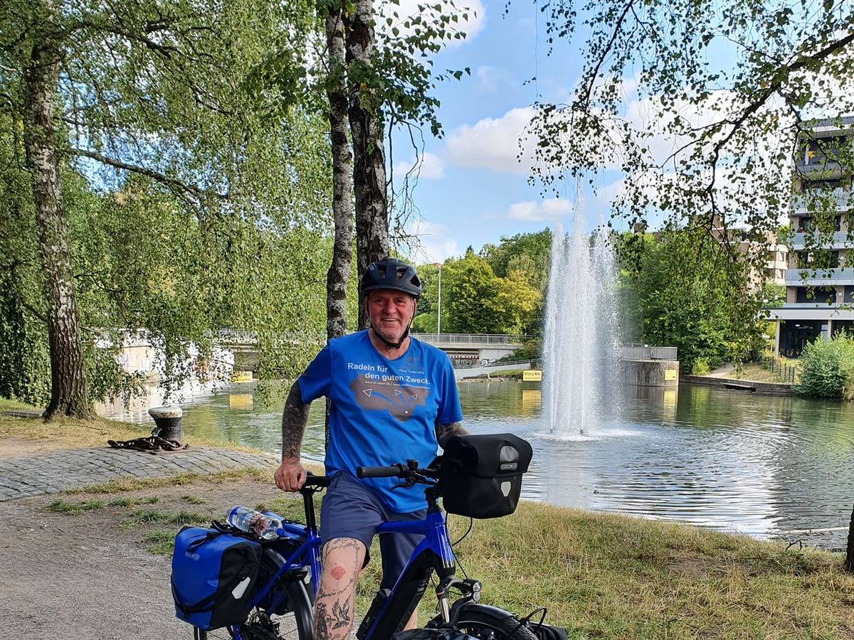 Oliver Trelenberg steht mit seinem Fahrrad vor einem See.