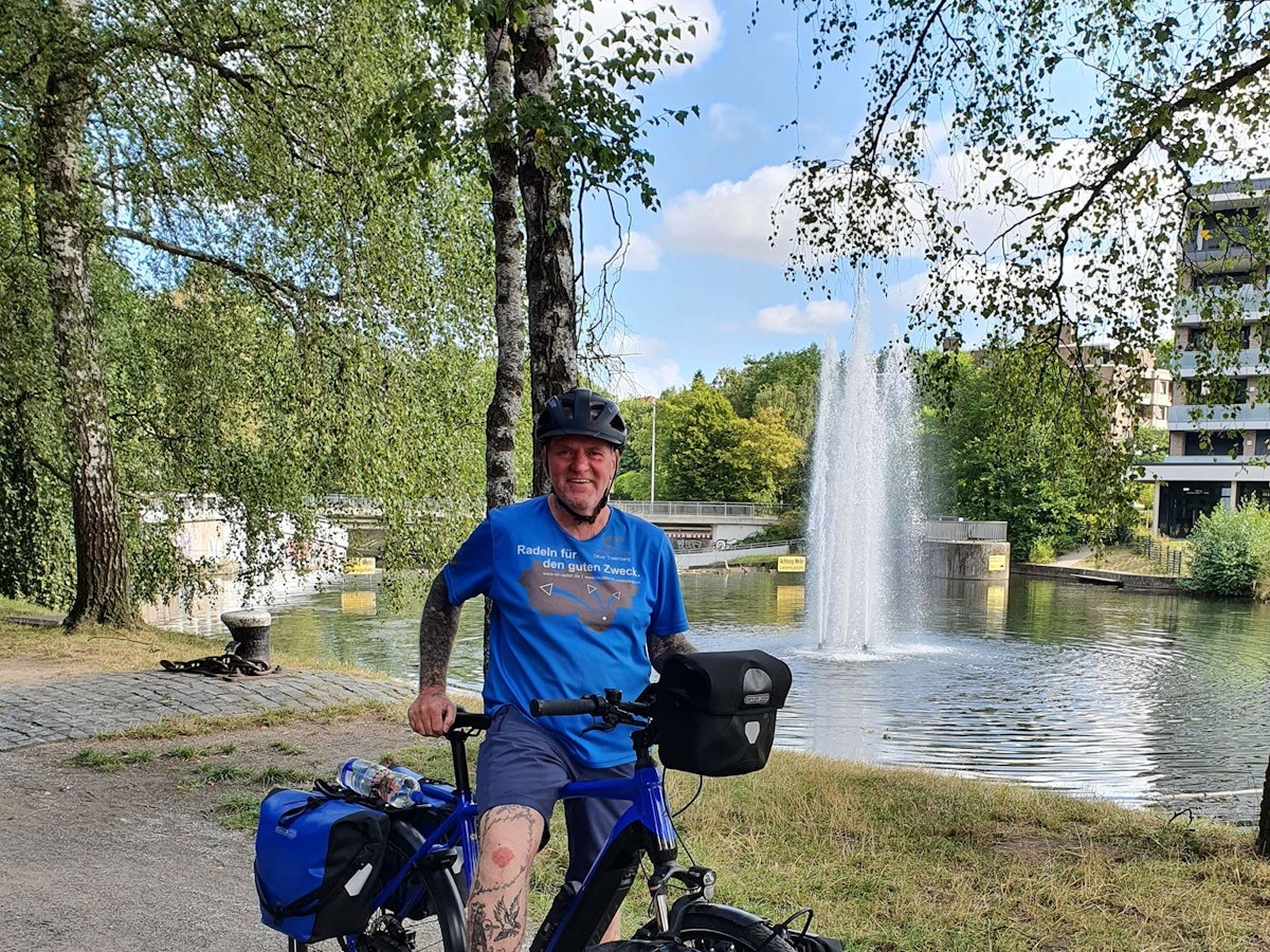 Oliver Trelenberg steht mit seinem Fahrrad vor einem See.