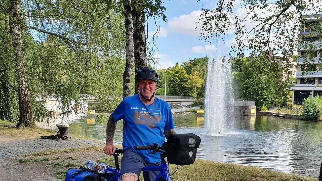 Oliver Trelenberg steht mit seinem Fahrrad vor einem See.