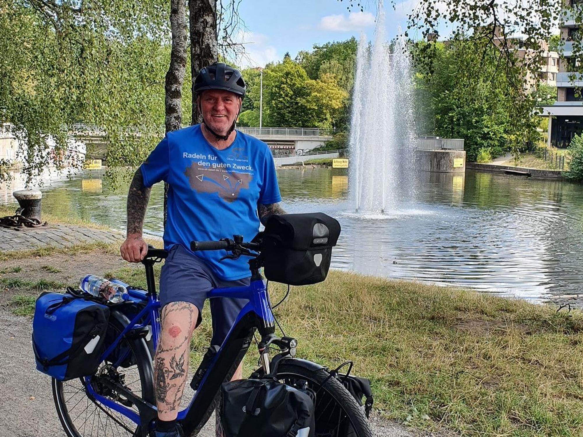 Oliver Trelenberg steht mit seinem Fahrrad vor einem See.