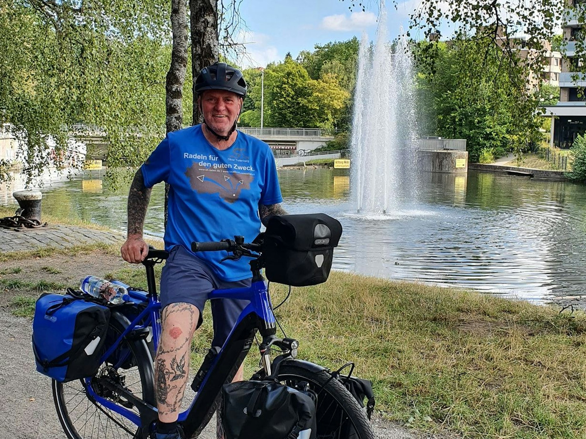 Oliver Trelenberg steht mit seinem Fahrrad vor einem See.