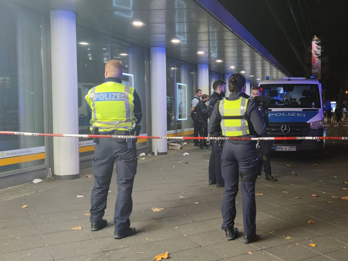 Einsatzkräfte der Polizei stehen in einem abgesperrten Bereich.