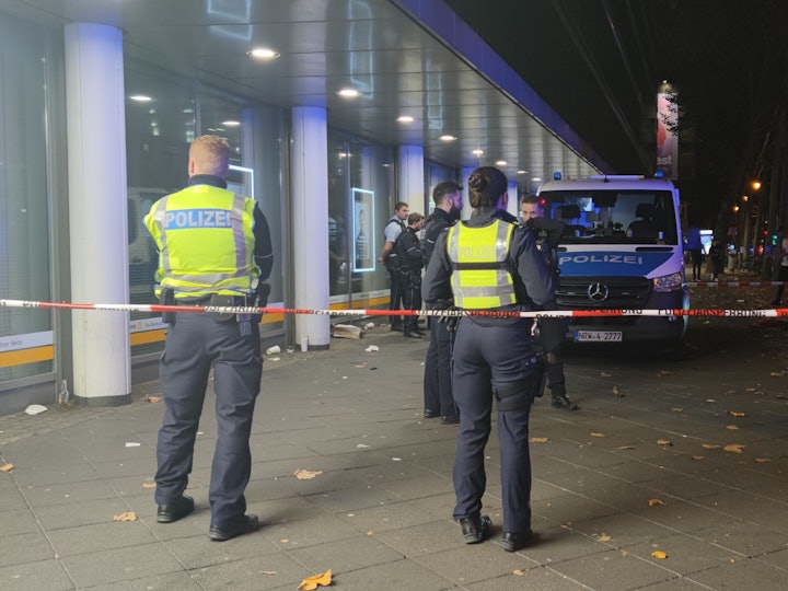 Einsatzkräfte der Polizei stehen in einem abgesperrten Bereich.