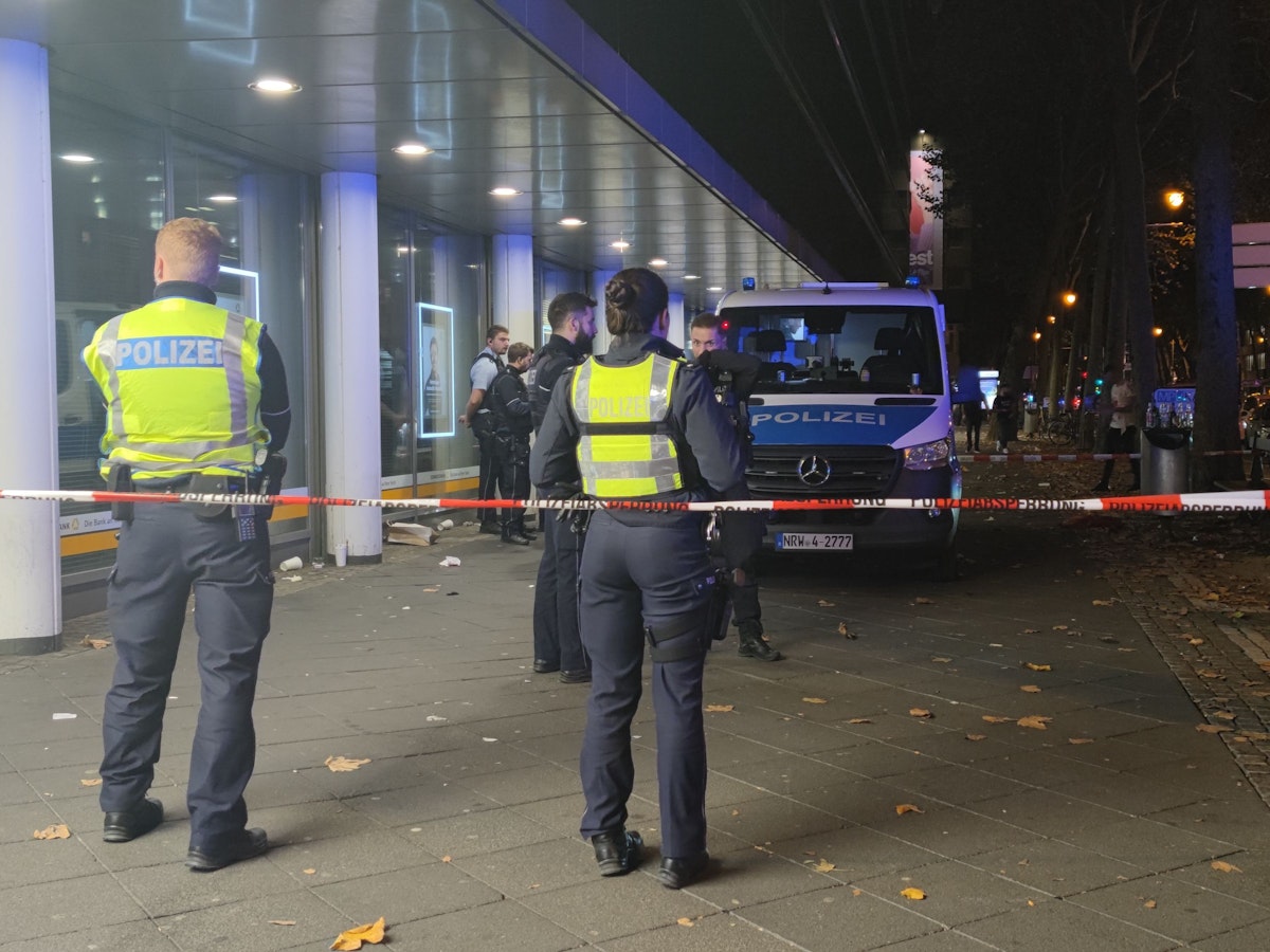 Einsatzkräfte der Polizei stehen in einem abgesperrten Bereich.