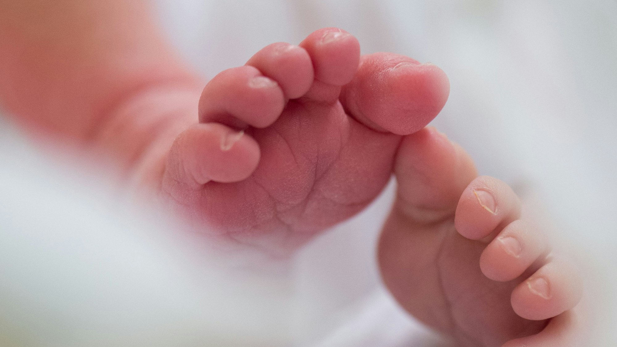 Ein Säugling liegt in einem Bett auf der Wochenstation.