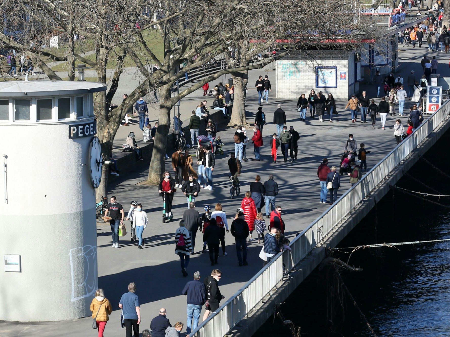 Menschen laufen über die Rheinpromenade in der Kölner Altstadt.