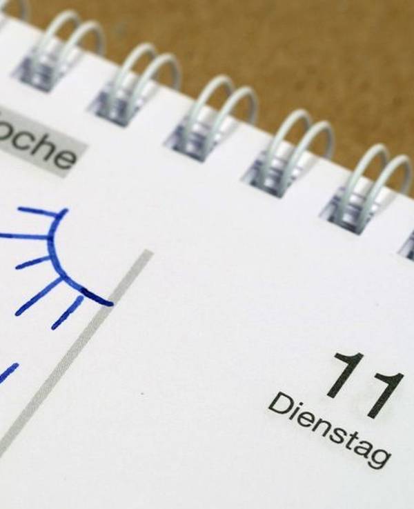 Auf einem Tisch liegt ein Kalender mit einem Eintrag „Urlaub“.