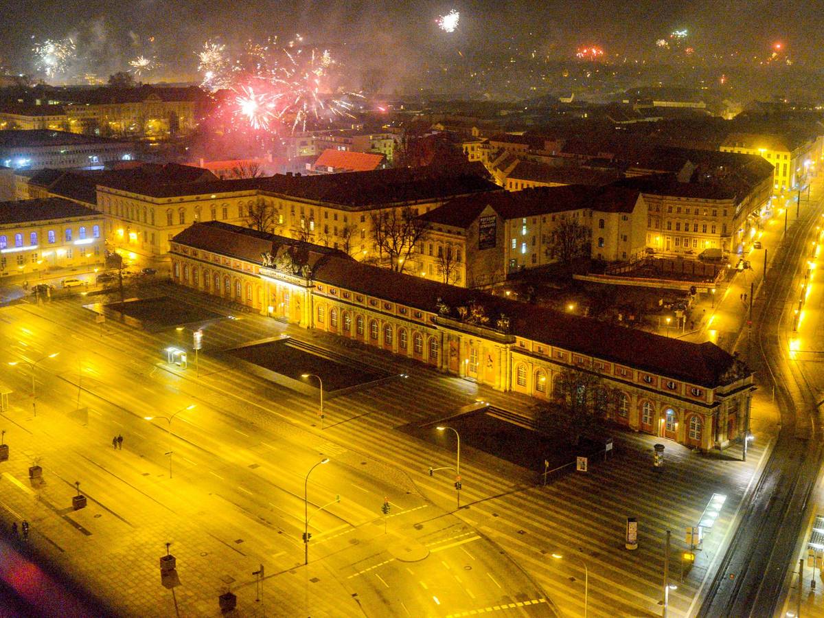 Blick vom Potsdamer Hotel Mercure auf die beleuchtete Breite Straße und das Filmmuseum, während in der Silvesternacht 2019 Feuerwerk in den Nachthimmel aufsteigt.