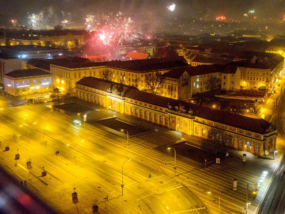Blick vom Potsdamer Hotel Mercure auf die beleuchtete Breite Straße und das Filmmuseum, während in der Silvesternacht 2019 Feuerwerk in den Nachthimmel aufsteigt.