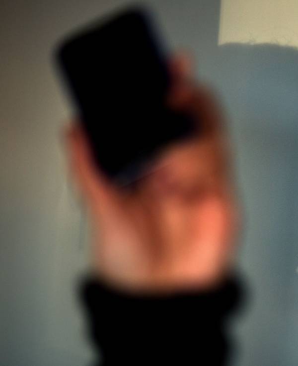 Eine Frau telefoniert mit ihrem Mobiltelefon und wirft dabei einen Schatten auf eine Wand.