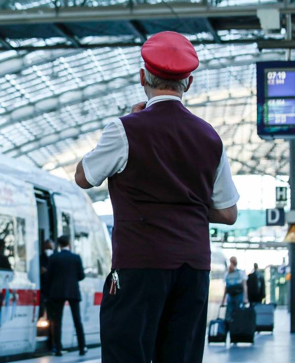 Ein Zugbegleiter gibt ein Abfahrtszeichen für einen ICE auf einem Bahnsteig im Berliner Hauptbahnhof.