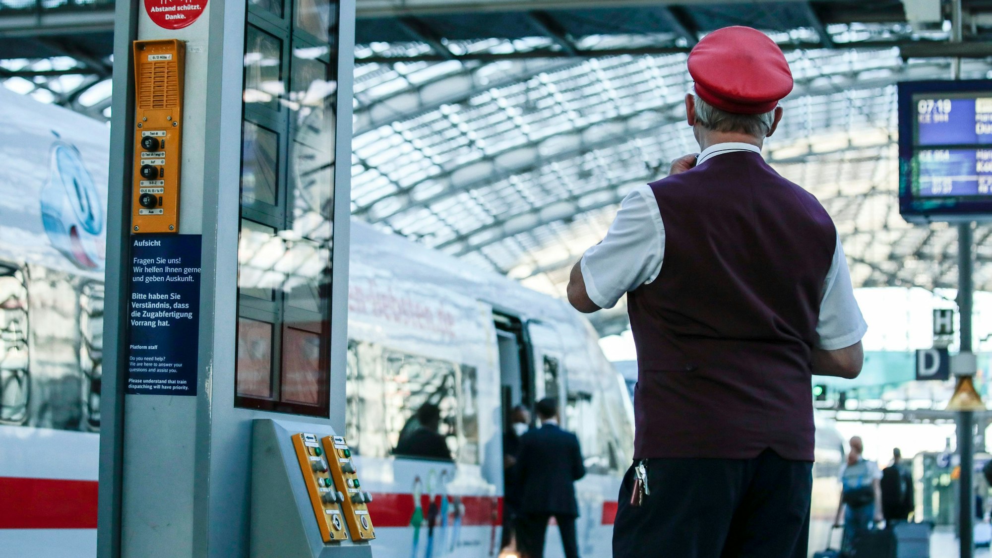 Ein Zugbegleiter gibt ein Abfahrtszeichen für einen ICE auf einem Bahnsteig im Berliner Hauptbahnhof.