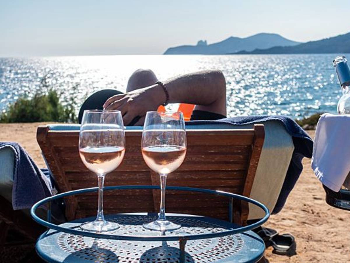 Ein sonniger Anblick! Während sich die Sonne auf dem Meer spiegelt, sorgen volle Weingläser für echtes Urlaubsfeeling. Die Aufnahme dient lediglich als Symbolfoto.
