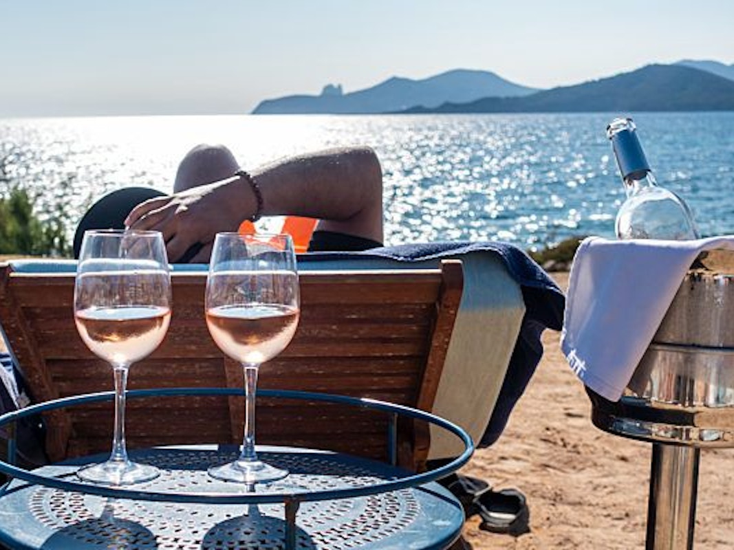 Ein sonniger Anblick! Während sich die Sonne auf dem Meer spiegelt, sorgen volle Weingläser für echtes Urlaubsfeeling. Die Aufnahme dient lediglich als Symbolfoto.