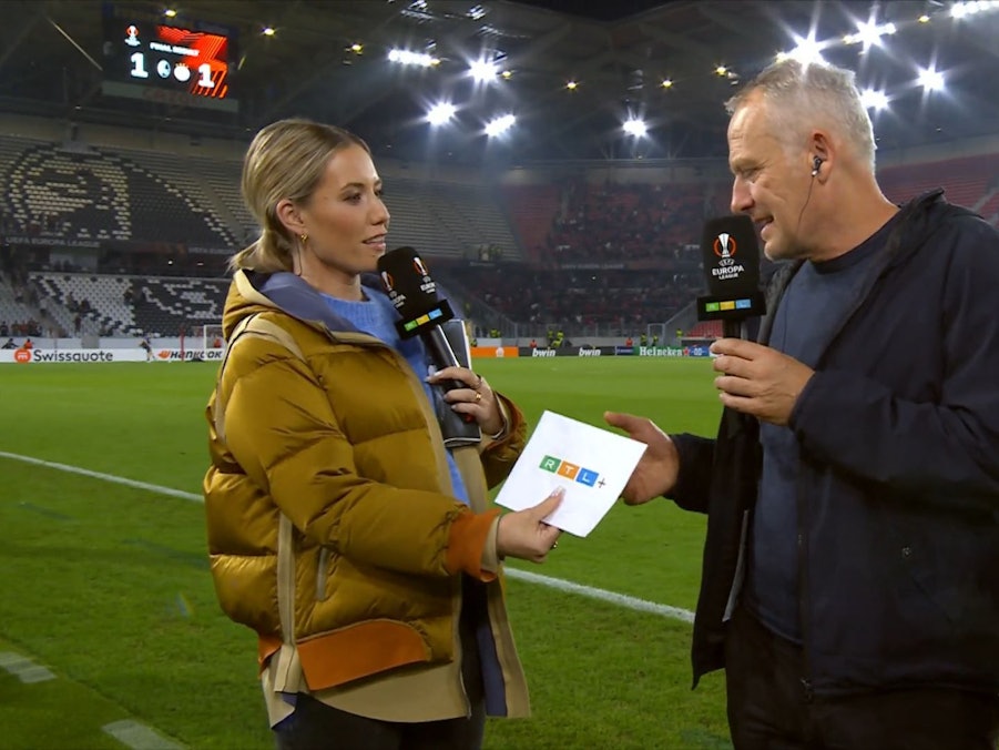 In Freiburg überreicht RTL-Moderatorin Laura Papendick SC-Trainer Christian Streich einen RTL+-Gutschein.