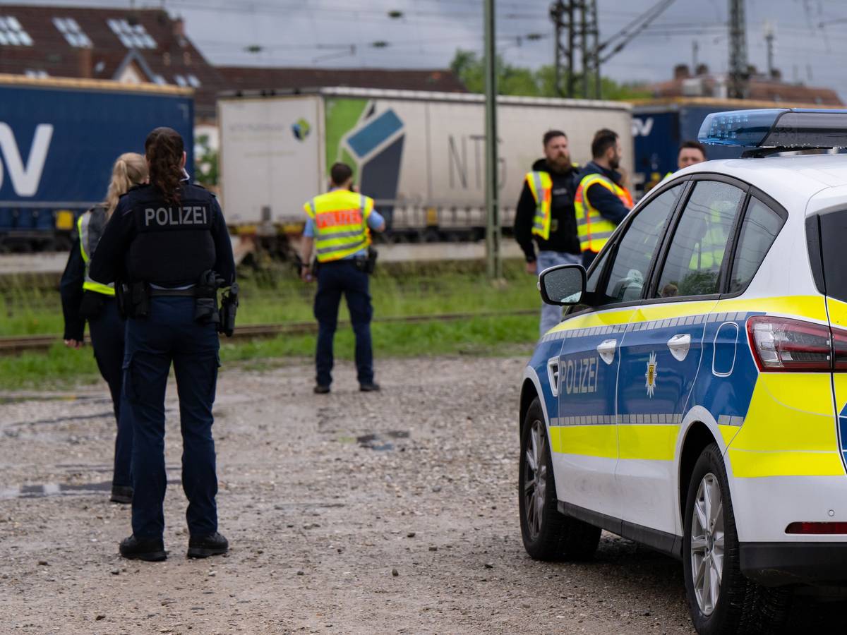 Einsatzkräfte der Polizei und Bundespolizei stehen an den Gleisen. Im Hintergrund ist ein Güterzug.