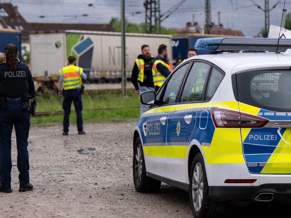Einsatzkräfte der Polizei und Bundespolizei stehen an den Gleisen. Im Hintergrund ist ein Güterzug.