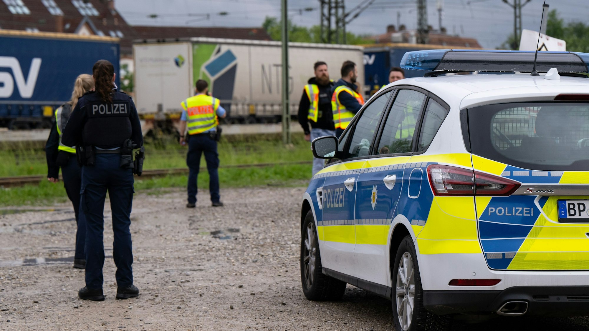 Einsatzkräfte der Polizei und Bundespolizei stehen an den Gleisen. Im Hintergrund ist ein Güterzug.
