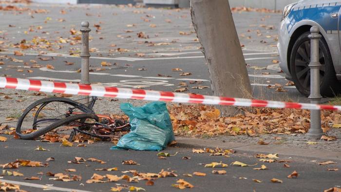 Ein zerstörtes Fahrrad liegt auf an einer Straße, die mit Flatterband der Polizei in dem Bereich abgesperrt wurde.