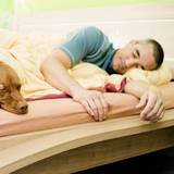 Ein Mann und sein Hund liegen gemeinsam im Bett