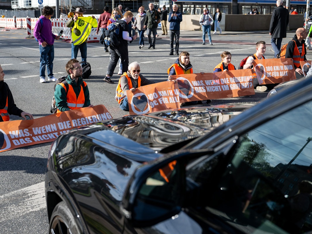 Klimaaktivisten haben sich am Karlsplatz in der Münchner Innenstadt auf die Fahrbahn geklebt und blockieren die Straße.